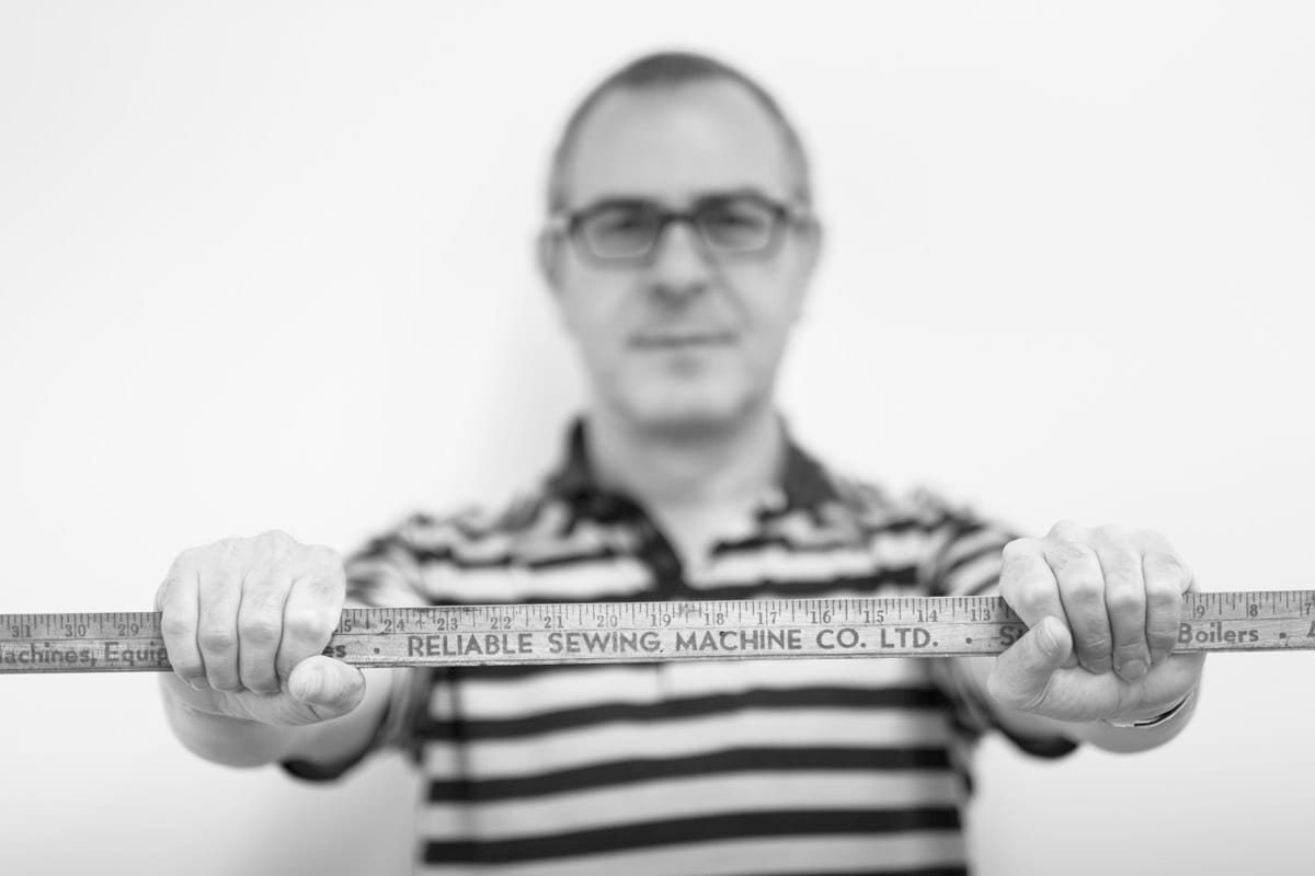 Corporate and professional photo of a man holding a long wooden ruler