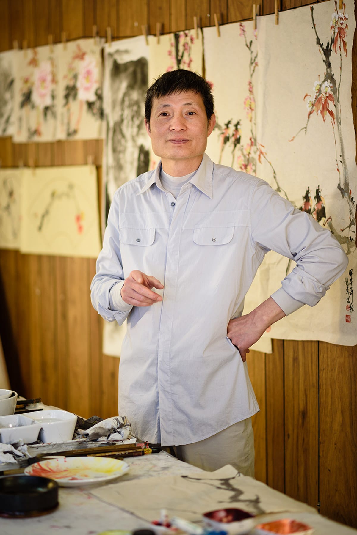 personal branding photo of a confident painter with his artwork hanging behind him