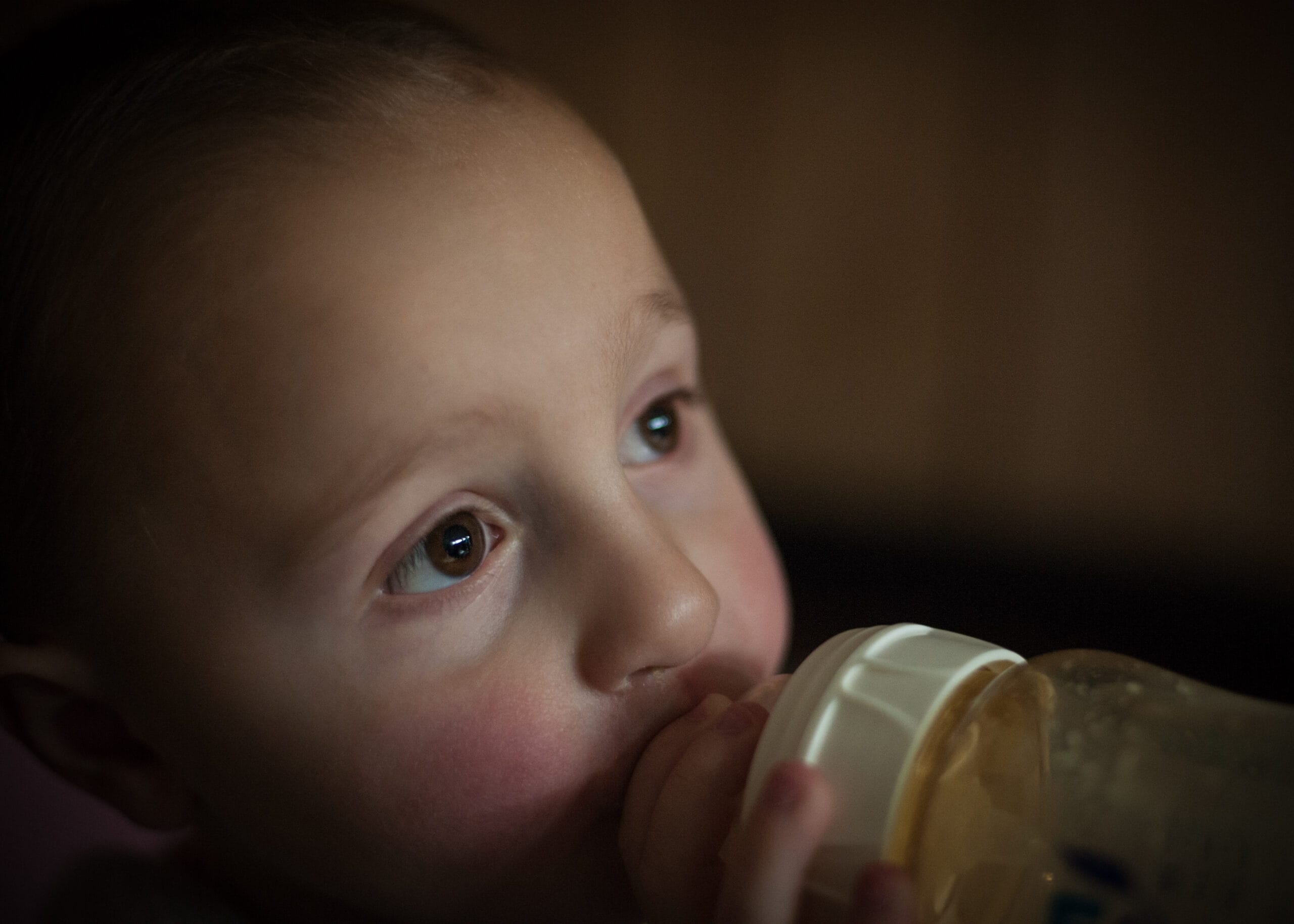 Children portrait photograph of a baby drinking milk from a bottle