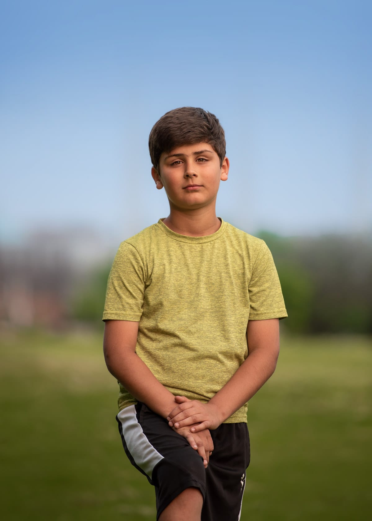 Portrait of a young boy standing with his hands placed on the leg