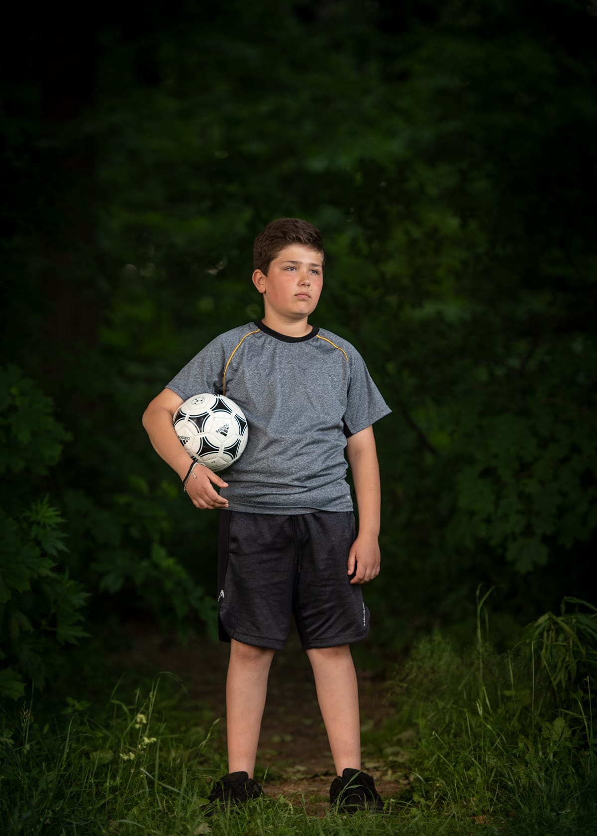 Youth portrait photograph of a young boy holding football
