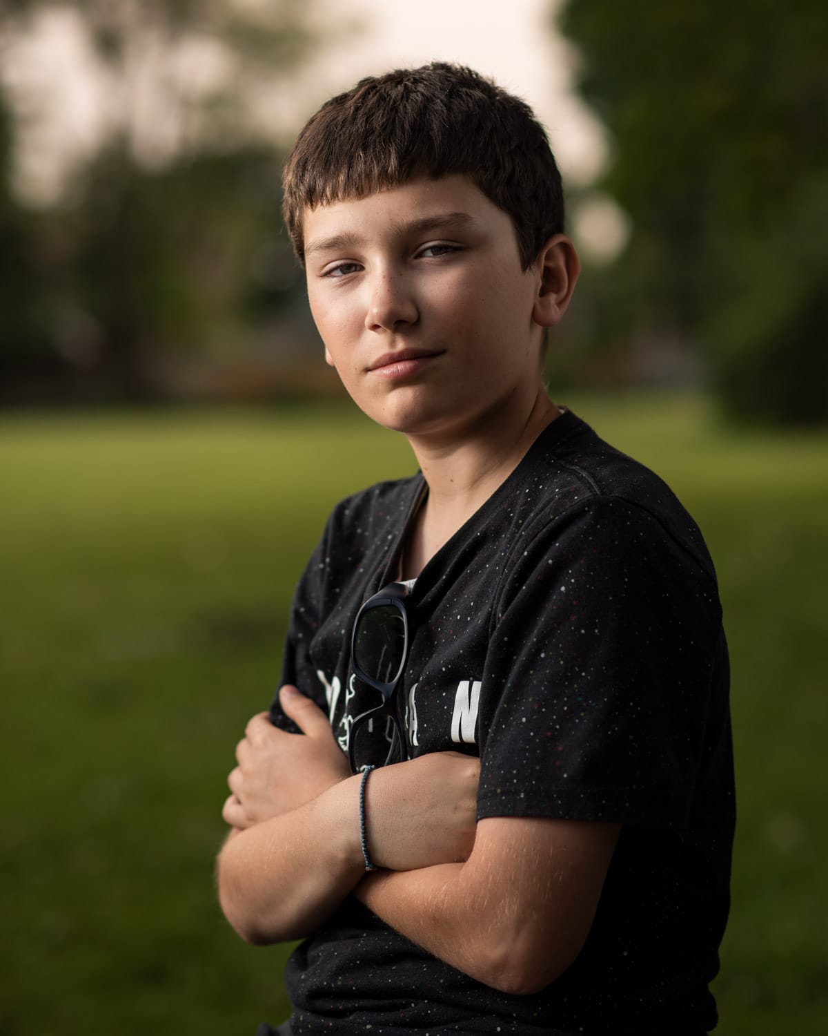 Portrait photograph of a young boy posing with his arms crossed