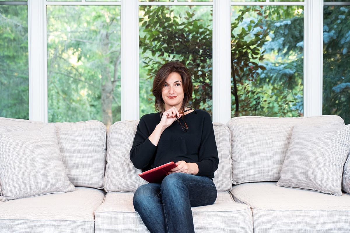 personal branding photo of a woman holding reading glasses sitting on a couch