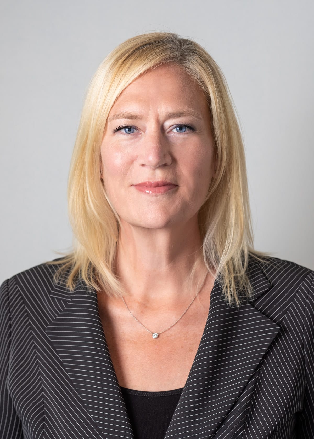 Corporate and professional headshot of woman in a striped suit