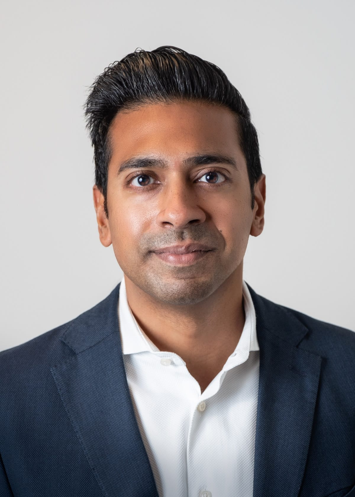 Corporate and professional headshot of a man in a casual suit